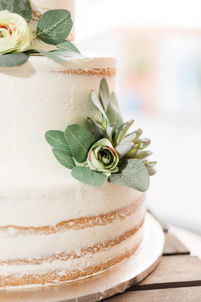 photo of a vanilla wedding cake with pieces of floral on the side. budget wedding
