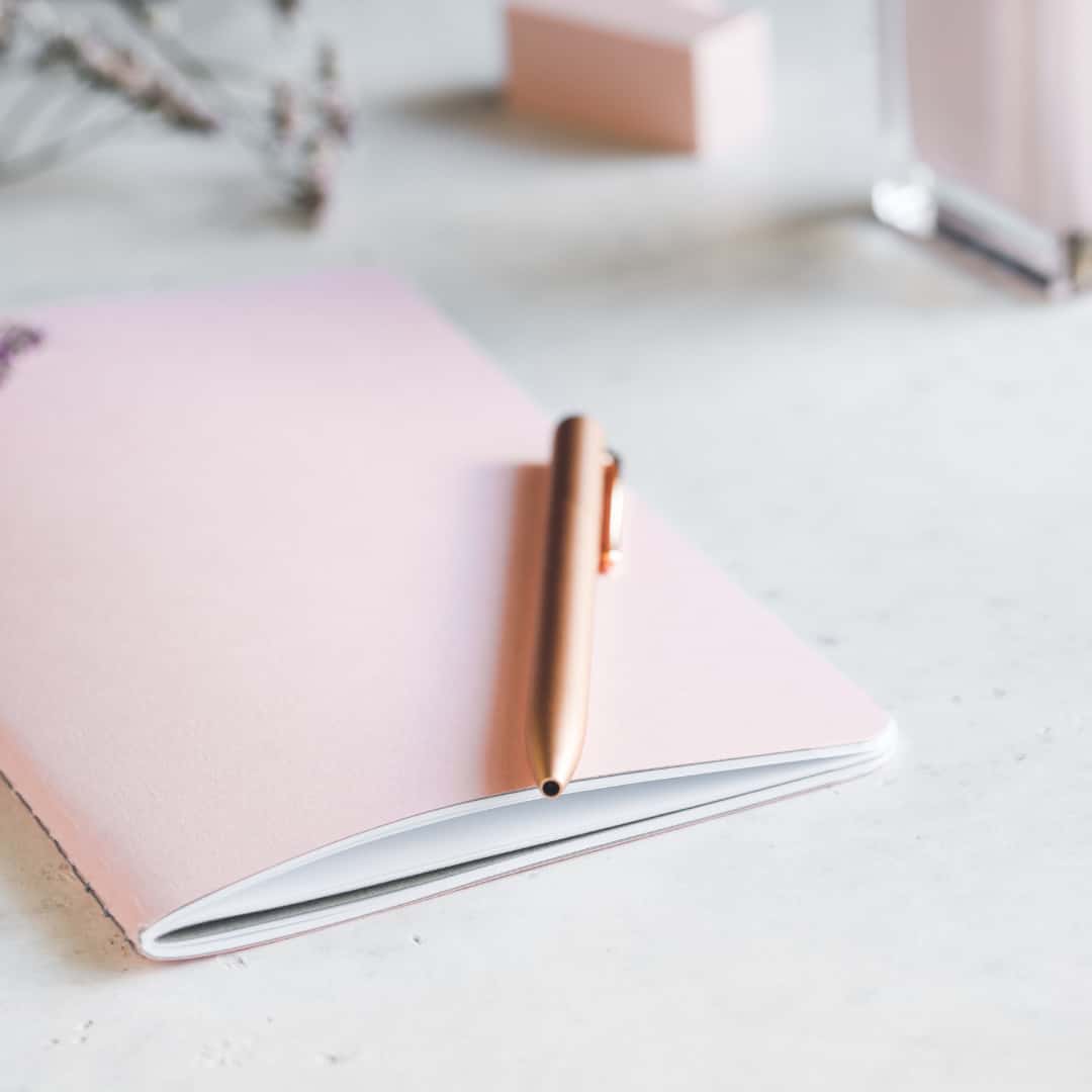 building healthy habits - pink notebook with a rose gold pen on a desk