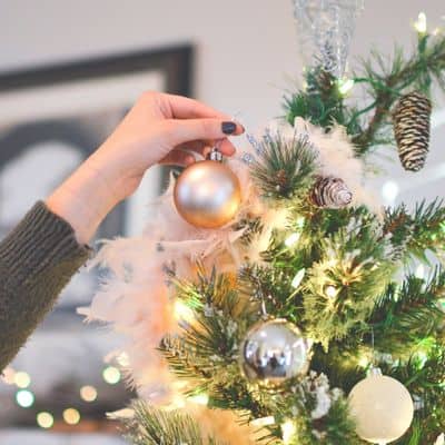 women putting ornament on Christmas tree. Christmas decorations for small apartments 
