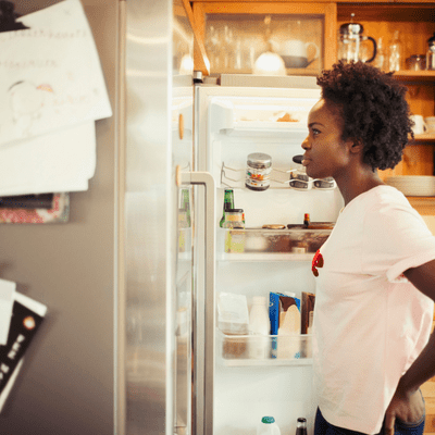 using vinegar to clean your fridge and freezer - women standing front of fridge 