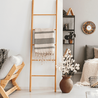 photo of a ladder with a throw pillow sitting on one of the handles. Apartment decorating budget. 