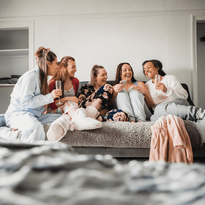 girls in their pajamma's laughing together drinking wine. What do girls do for Galentines day?
