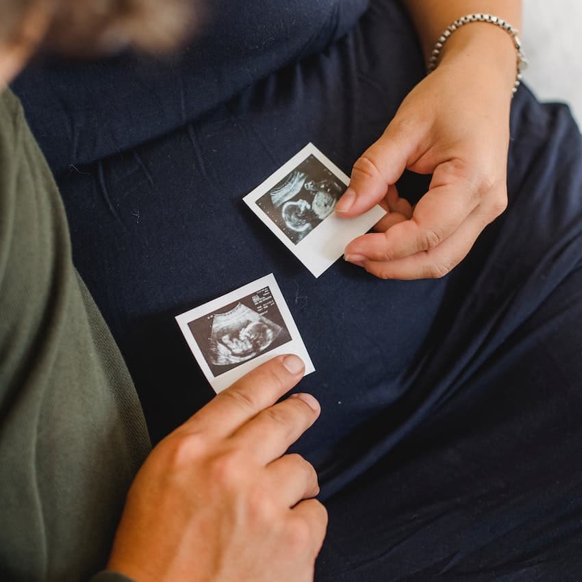 men and women sitting on the couch while holding a sonogram picture.  How to plan for a family. 
