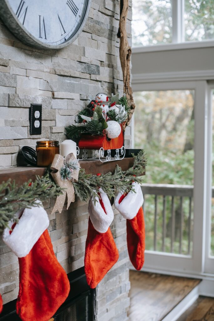 photo of three red Christmas stocking hanging by a fireplace with a mistletoe garland. Christmas stocking stuffers for men