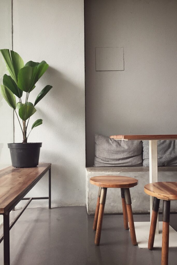 photo of a dining room with cement walls, green plant, and brown wooden stools. Tips for apartment hunting. 