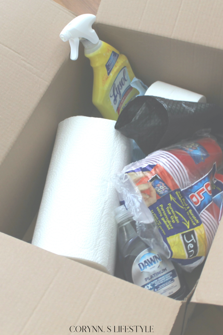 photo of a box with multipurpose spray, paper towel, plastic cups. First night moving box