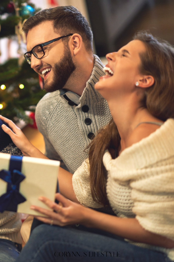 photo of a couple who are holding gift while laughing. White elephant gift ideas for under $100
